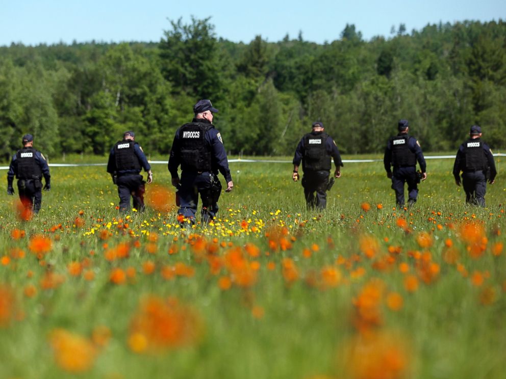 PHOTO: Law enforcement officers walk in a field along Route 3, June 13, 2015, in Saranac, N.Y. 