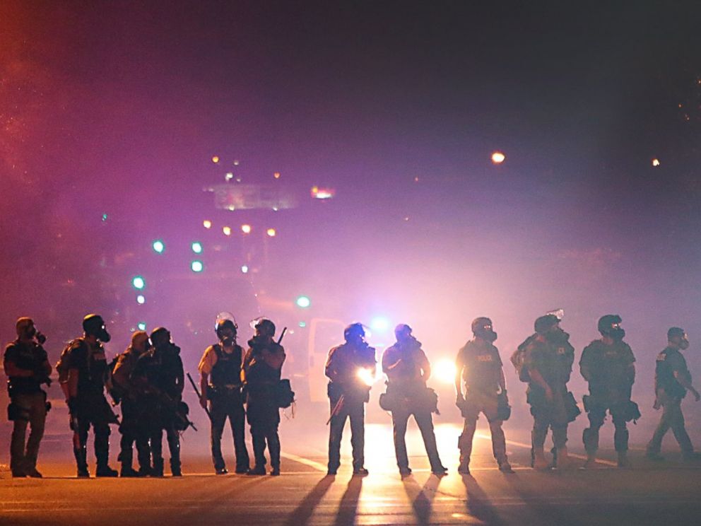 PHOTO: Police officers work their way north on West Florissant Avenue in Ferguson, Mo., clearing the road of people, Aug. 13, 2014.