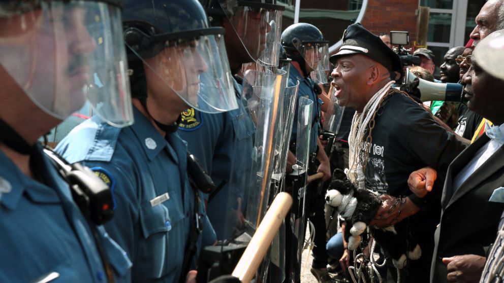 PHOTO: Protester Anthony Shahid leads marchers as they confront Missouri State Highway Patrol trooper in front of the Ferguson police station, Aug. 11, 2014, in Ferguson, Mo.