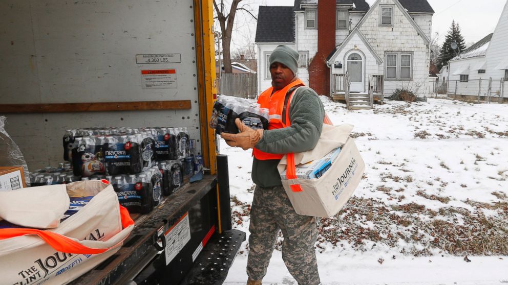 Michigan National Guard Specialist Lonnie Walker unloads bottled water and filters to distribute to residents, Jan. 21, 2016, in Flint, Mich. 