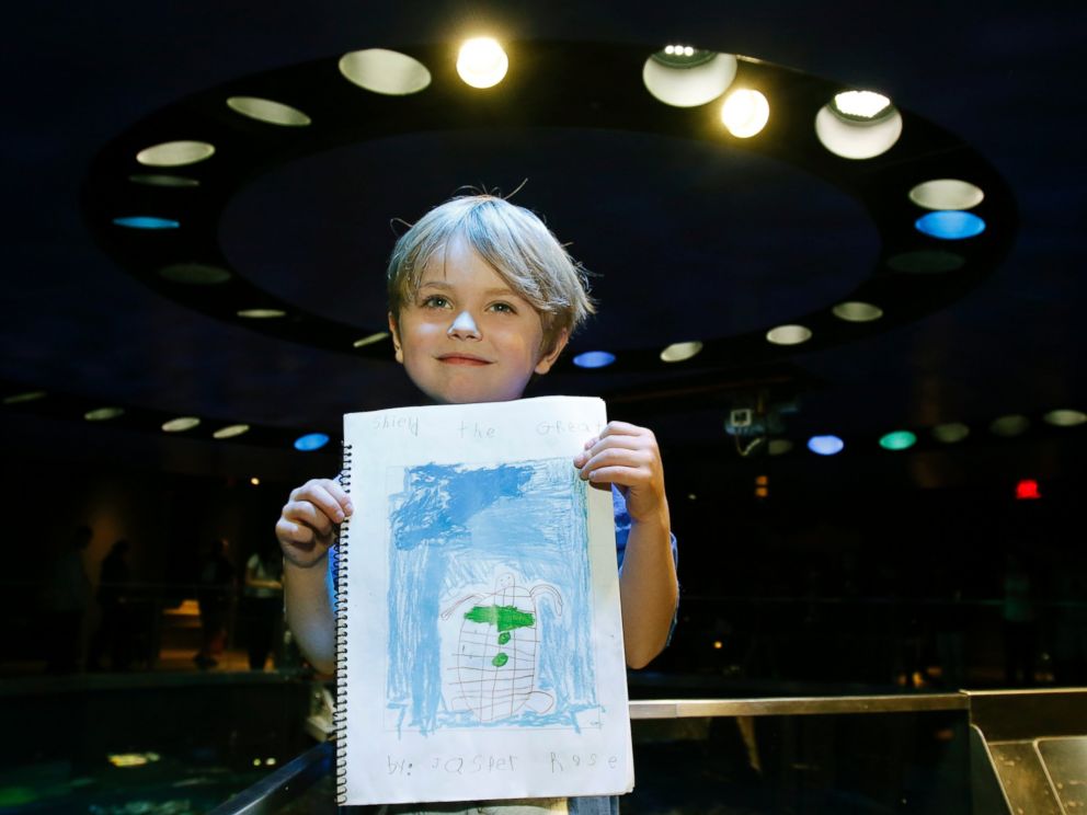 PHOTO: Jasper Rose, of Watertown, Mass., holds a booklet he created about turtles as he stands by the main tank at the New England Aquarium, April 22, 2016, in Boston.