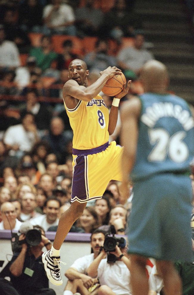 PHOTO: Los Angeles Lakers Kobe Bryant looks for a teammate to pass to as Minnesota Timberwolves James Robinson looks on during Bryant's first game at the Forum in Inglewood, California, Nov. 3, 1996. 