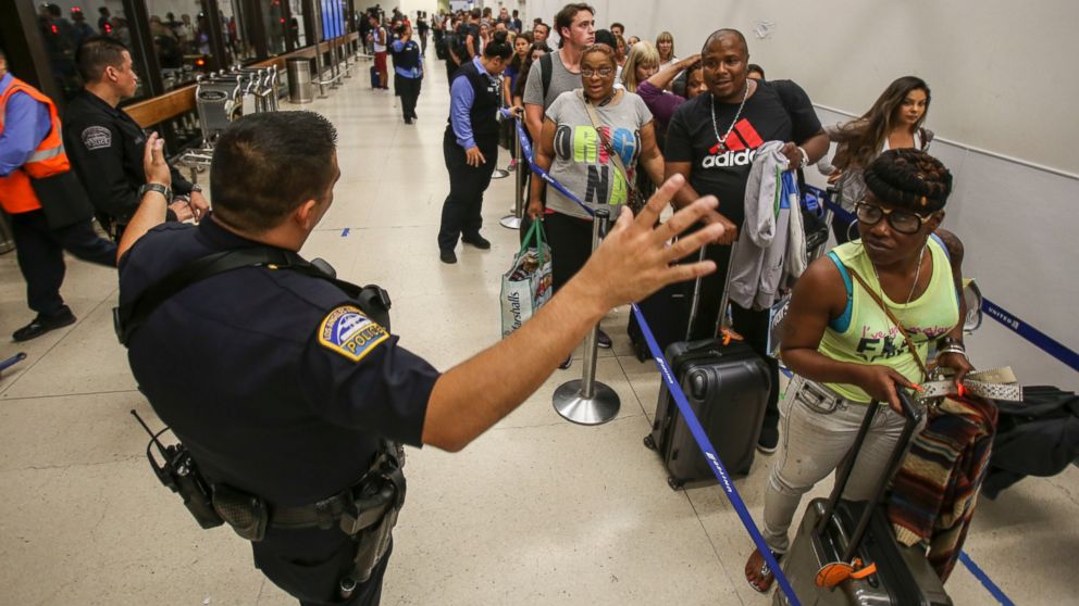 PHOTO: Police officers stand guard as passengers wait in line at Terminal 7 in Los Angeles International Airport, Aug. 28, 2016.