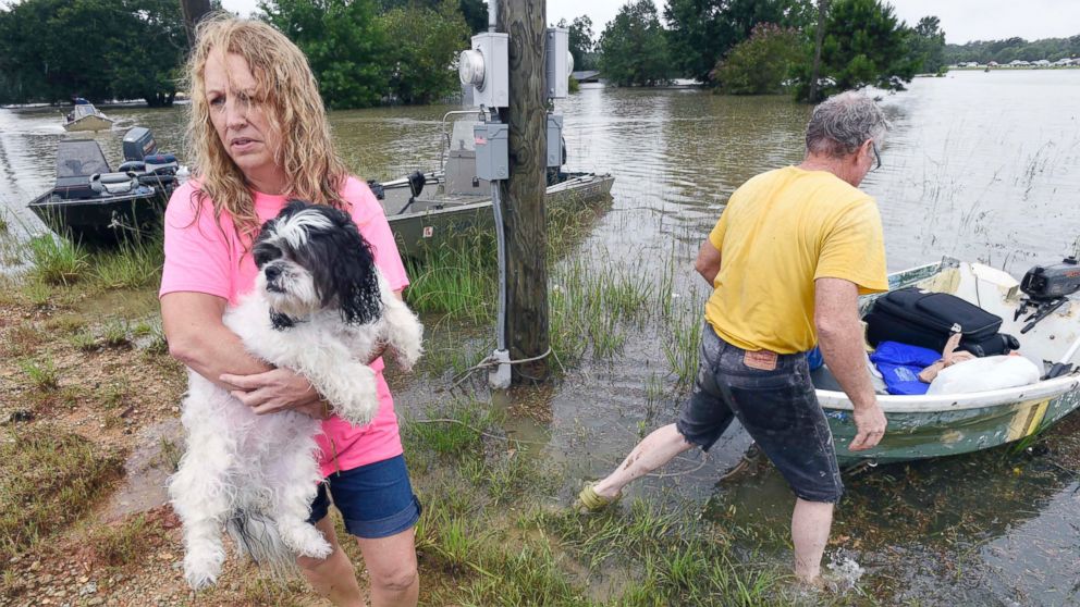 PHOTO: Tammie Wise holds her dog Mikey, after Jeffrey Lesage, right, boated them to safety in Central, Louisiana, Aug. 13, 2016.