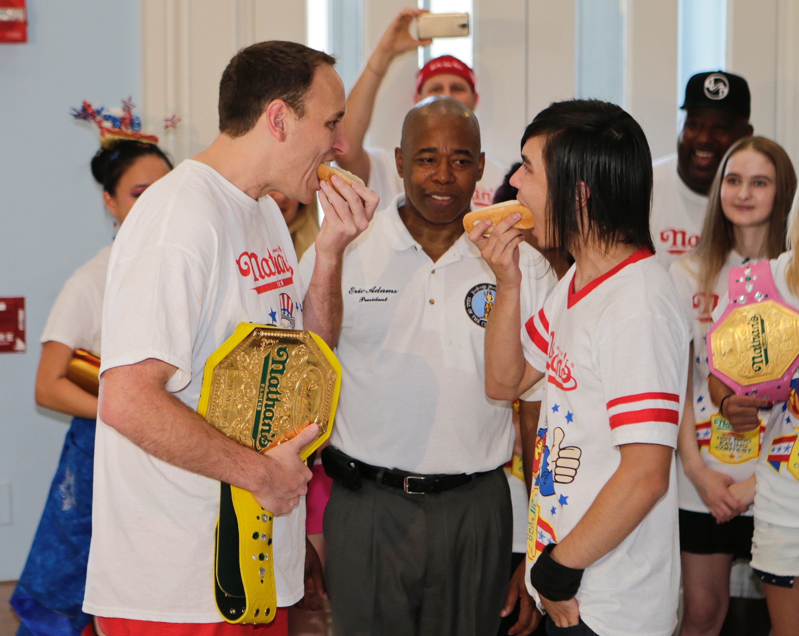 PHOTO: Brooklyn Borough President Eric Adams watches Joey Chestnut, left, and Matt Stonie, right, during a news conference to promote the upcoming Nathan's Famous Fourth of July Hot-Dog Eating Contest, July 3, 2015, at Brooklyn Borough Hall in New York. 