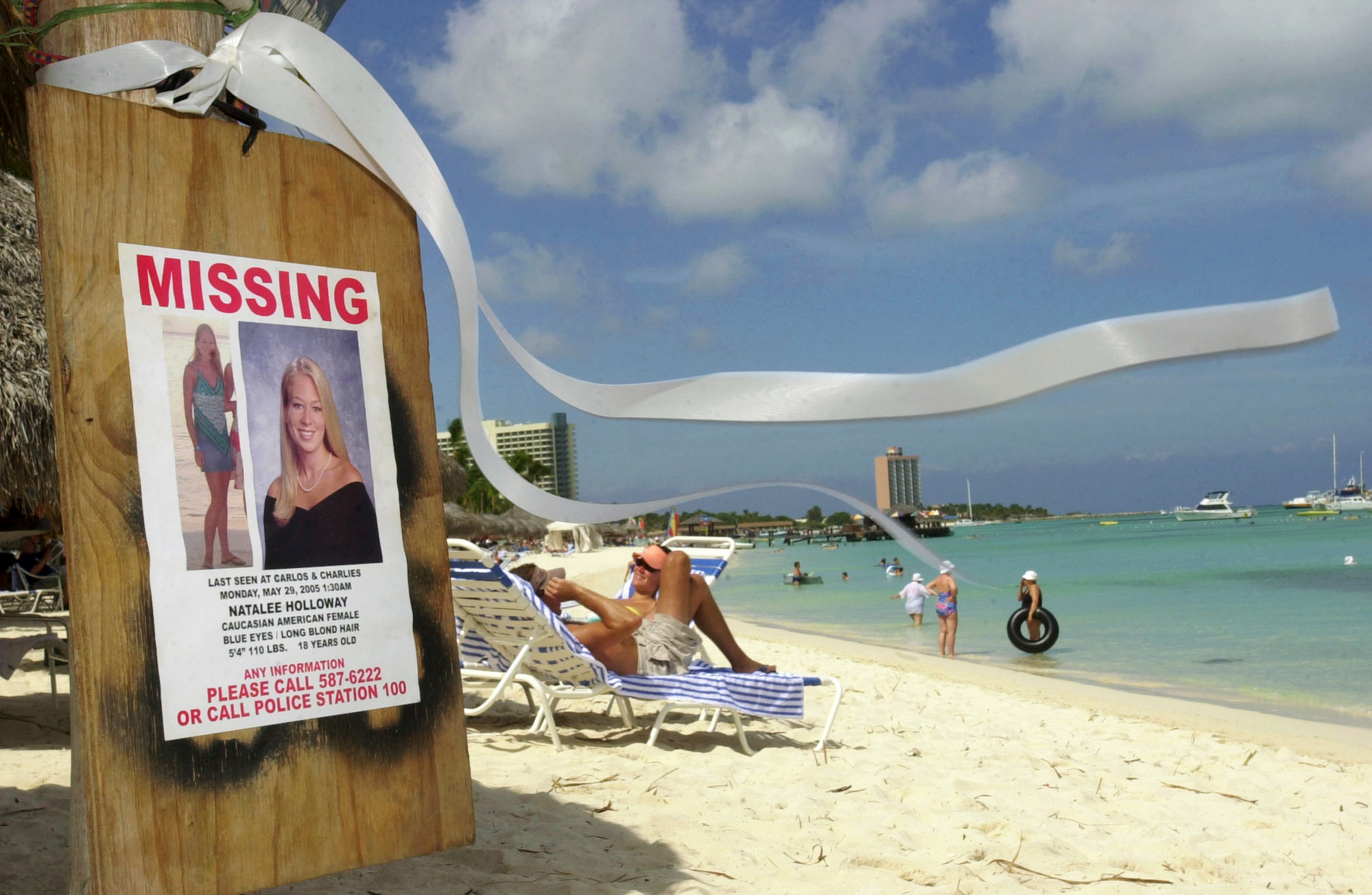 PHOTO: A missing poster for Natalee Holloway, a high school graduate of Mountain Brook, Alabama who disappeared while on a graduation trip to Aruba on May 30, 2005, is seen on Palm Beach where tourists sunbathe in Aruba, June 10, 2005.