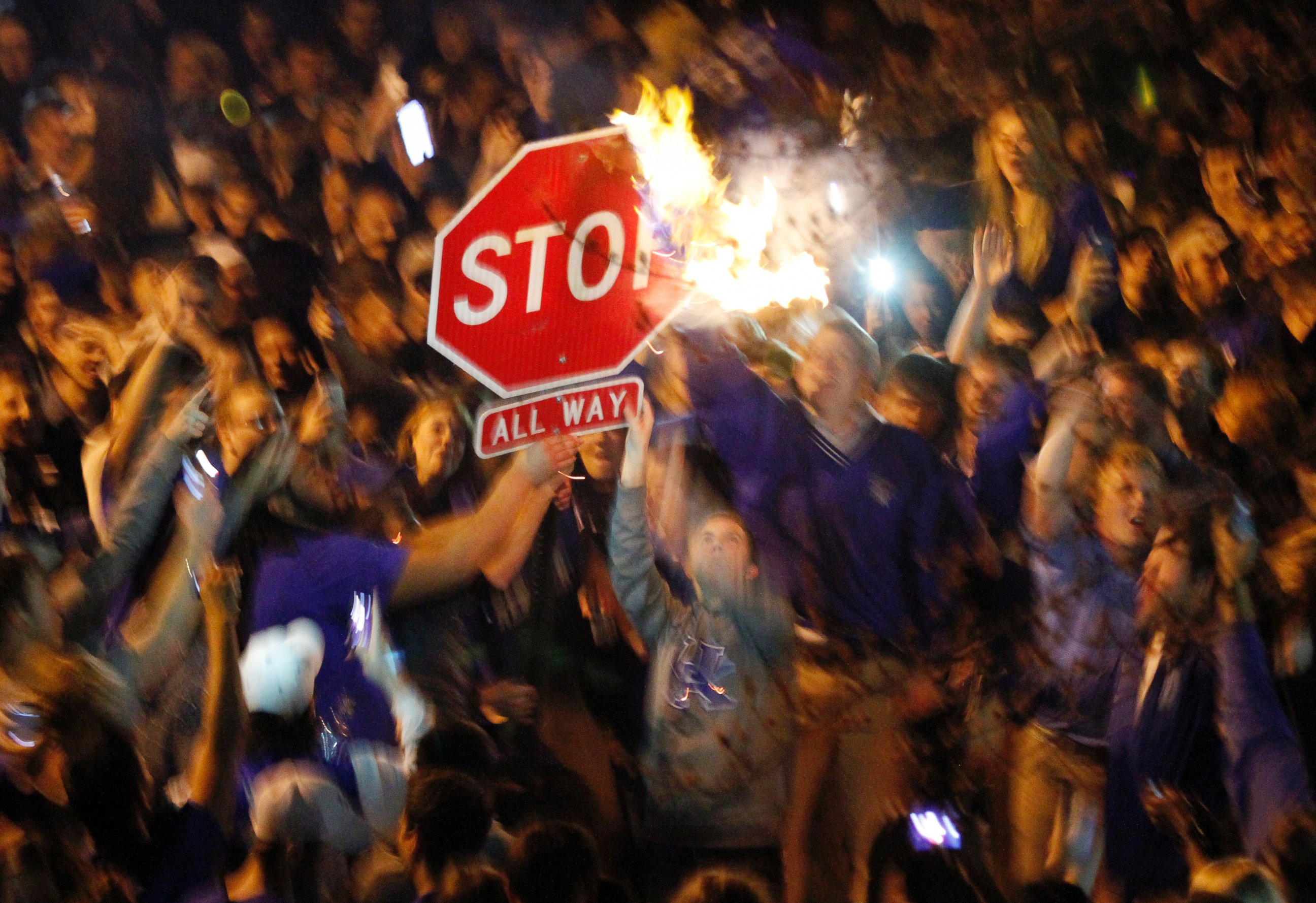 PHOTO: Kentucky fans wave a stop sign with a burning shirt near the University of Kentucky campus, Saturday, April 5, 2014, in Lexington, Ky.