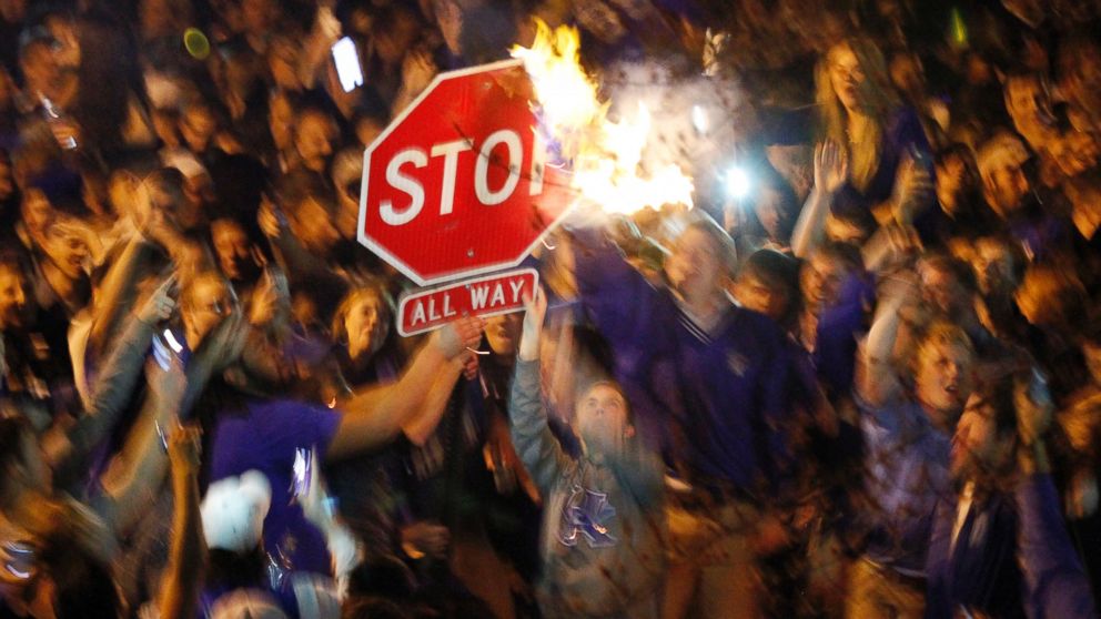 PHOTO: Kentucky fans wave a stop sign with a burning shirt near the University of Kentucky campus, Saturday, April 5, 2014, in Lexington, Ky.