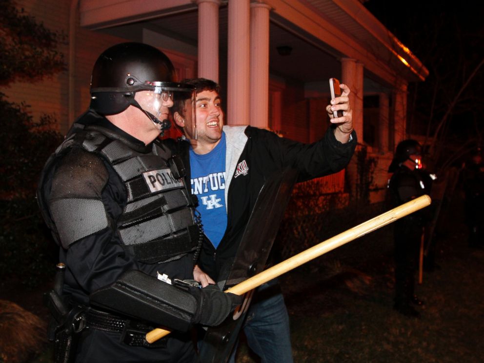 PHOTO: Eastern Kentucky University junior Eric Kuertz, right, takes a selfie with UK Police officer Lt. Greg Hall as Kentucky fans react to their teams semi-final victory on State St., Saturday, April 5, 2014, in Lexington, Ky.