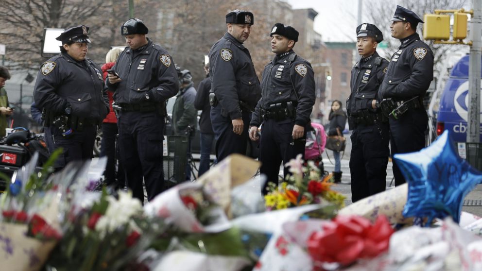New York City police officers gather near a makeshift memorial near the site where fellow officers Rafael Ramos and Wenjian Liu were murdered in the Brooklyn borough of New York, Dec. 22, 2014.