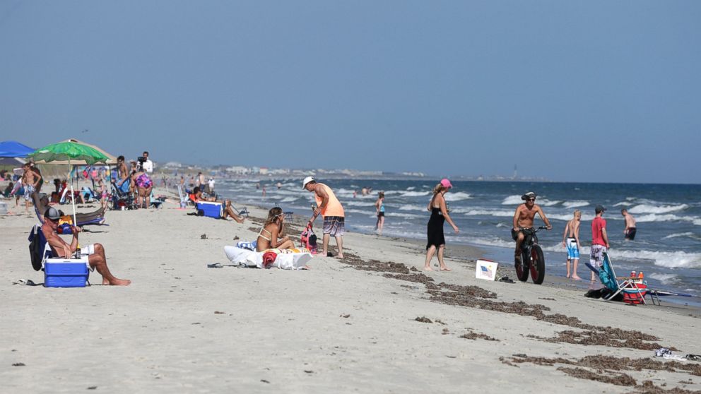 Vacationers relax on the bench and in the surf in Oak Island, N.C.,  June 15, 2015. 