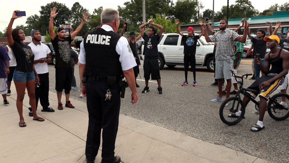 Protestors blocking Florissant Road raise their hands after being approached by police officers who asked them to stop blocking the street in front of the Ferguson police department on Aug. 10, 2014, one day after a Ferguson officer shot and killed Michael Brown. 