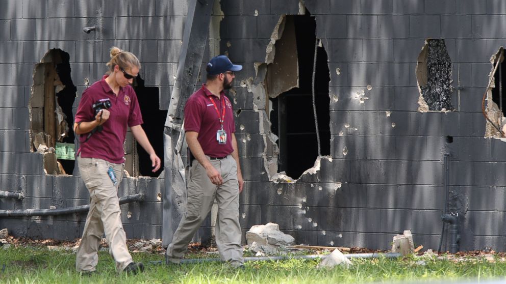 Investigators from the office of the medical examiner investigate on the west side of Pulse nightclub where a gunman opened fire on Sunday morning, June 12, 2016, in Orlando, Fla.
