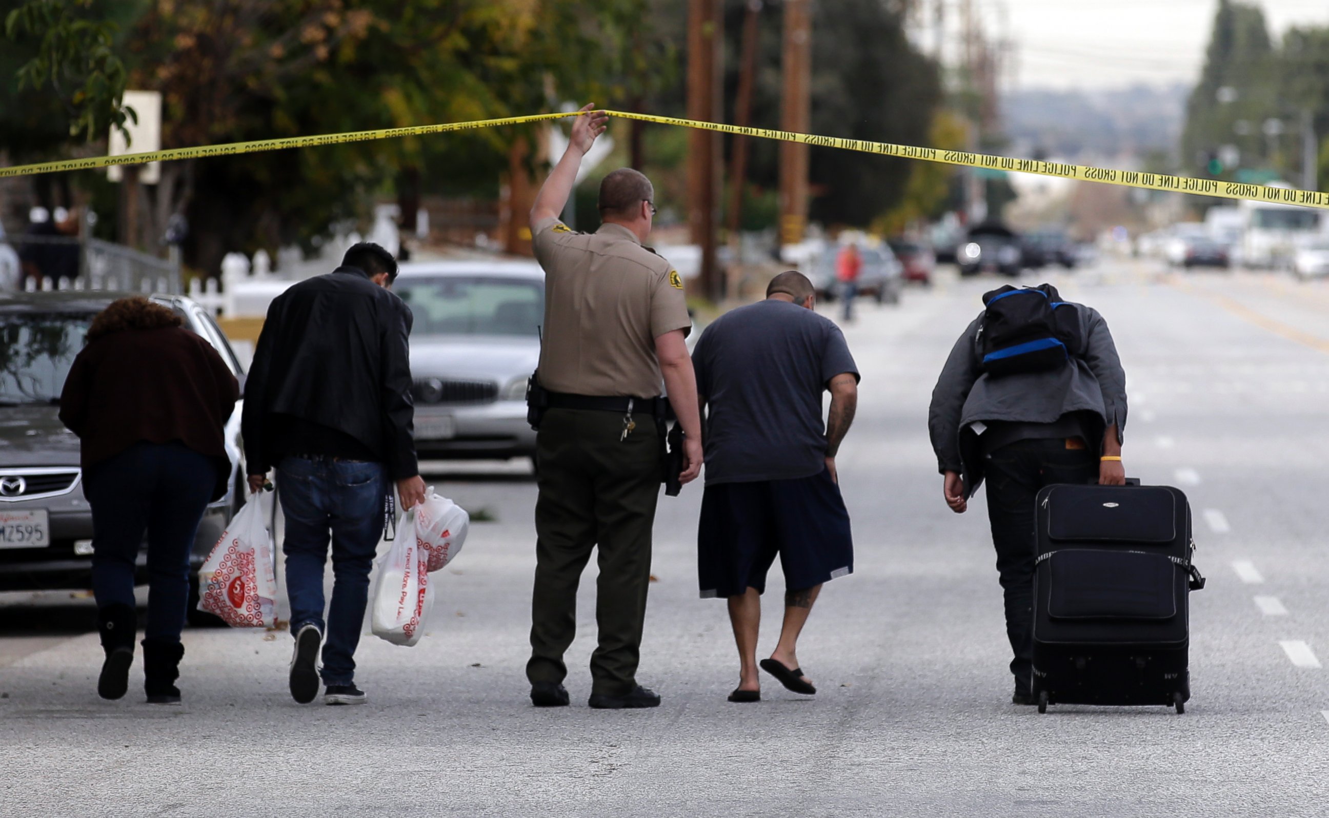 PHOTO: Residents are escorted to their homes near a Black SUV that was involved in a police shootout with shooting suspects, Dec. 3, 2015, in San Bernardino, Calif.