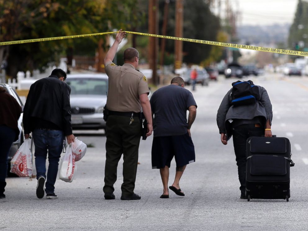 PHOTO: Residents are escorted to their homes near a Black SUV that was involved in a police shootout with shooting suspects, Dec. 3, 2015, in San Bernardino, Calif.