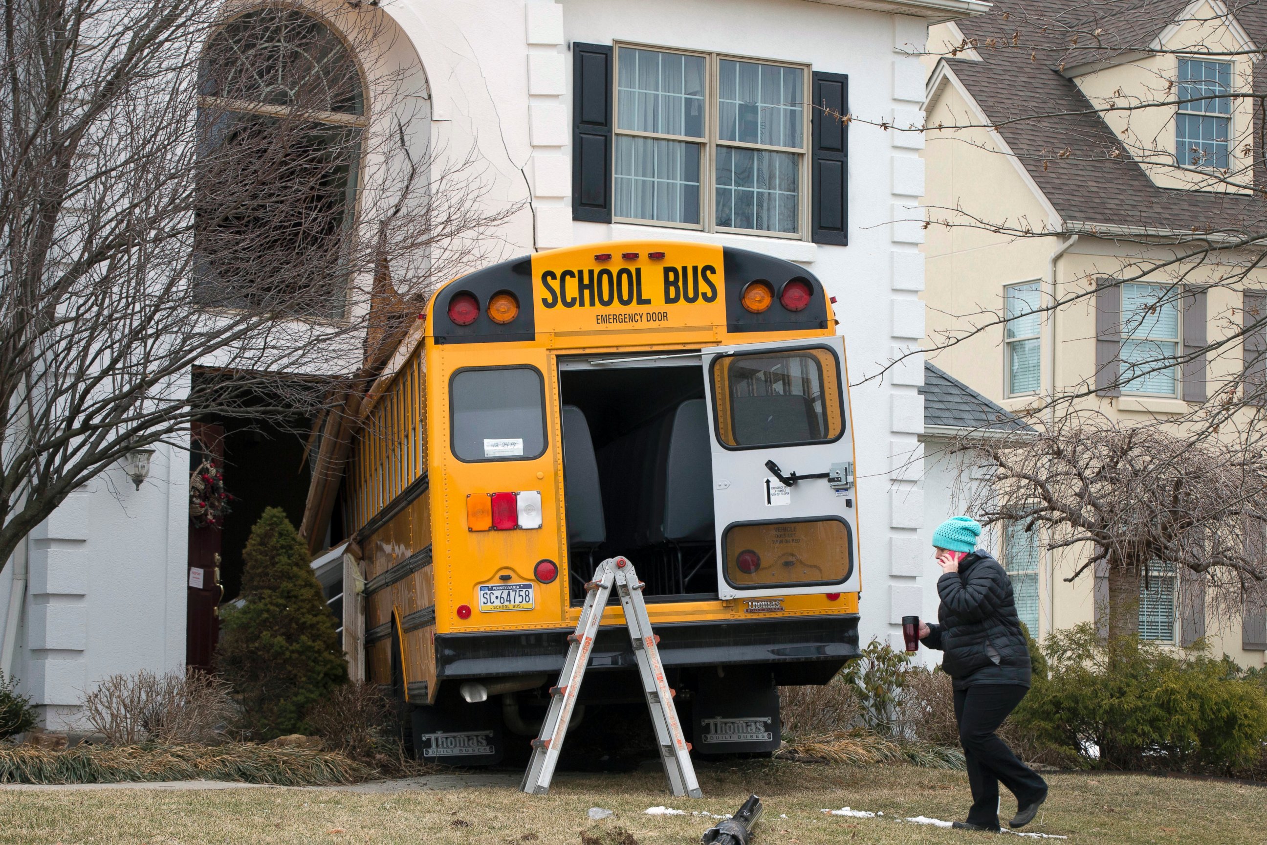 PHOTO: A woman walks past a school bus that crashed into a home in Blue Bell, Pa., March 24, 2015.