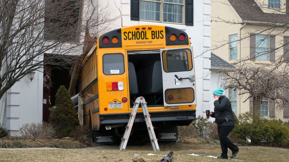 PHOTO: A woman walks past a school bus that crashed into a home in Blue Bell, Pa., March 24, 2015.