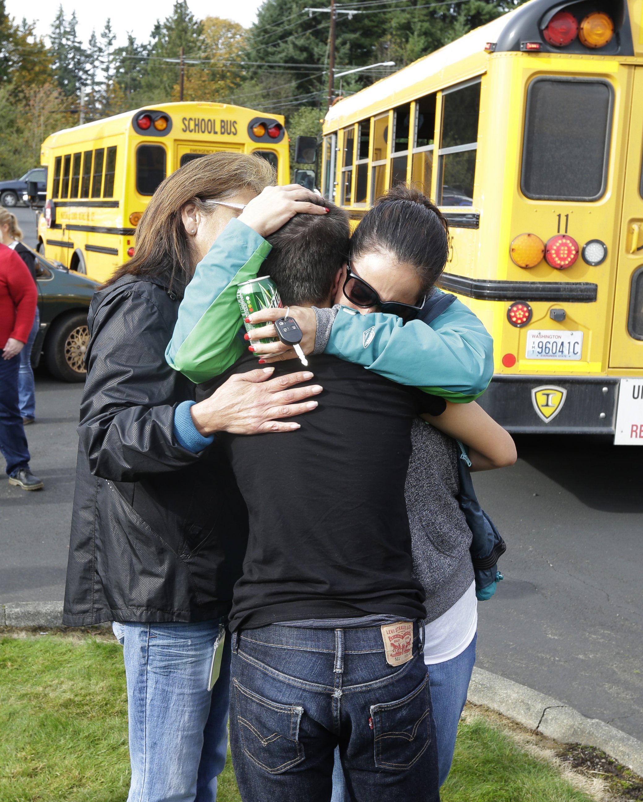 PHOTO: People embrace in front of school buses at a church, where students were taken to be reunited with parents, following a shooting at Marysville Pilchuck High School in Marysville, Wash. on Oct. 24, 2014.