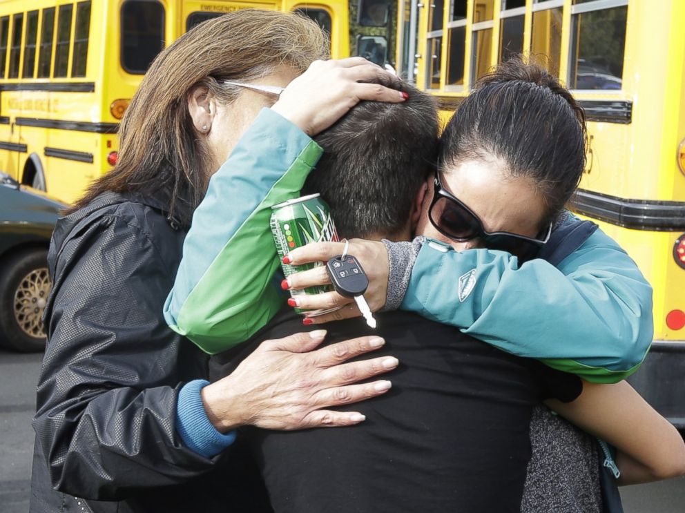 PHOTO: People embrace in front of school buses at a church, where students were taken to be reunited with parents, following a shooting at Marysville Pilchuck High School in Marysville, Wash. on Oct. 24, 2014.