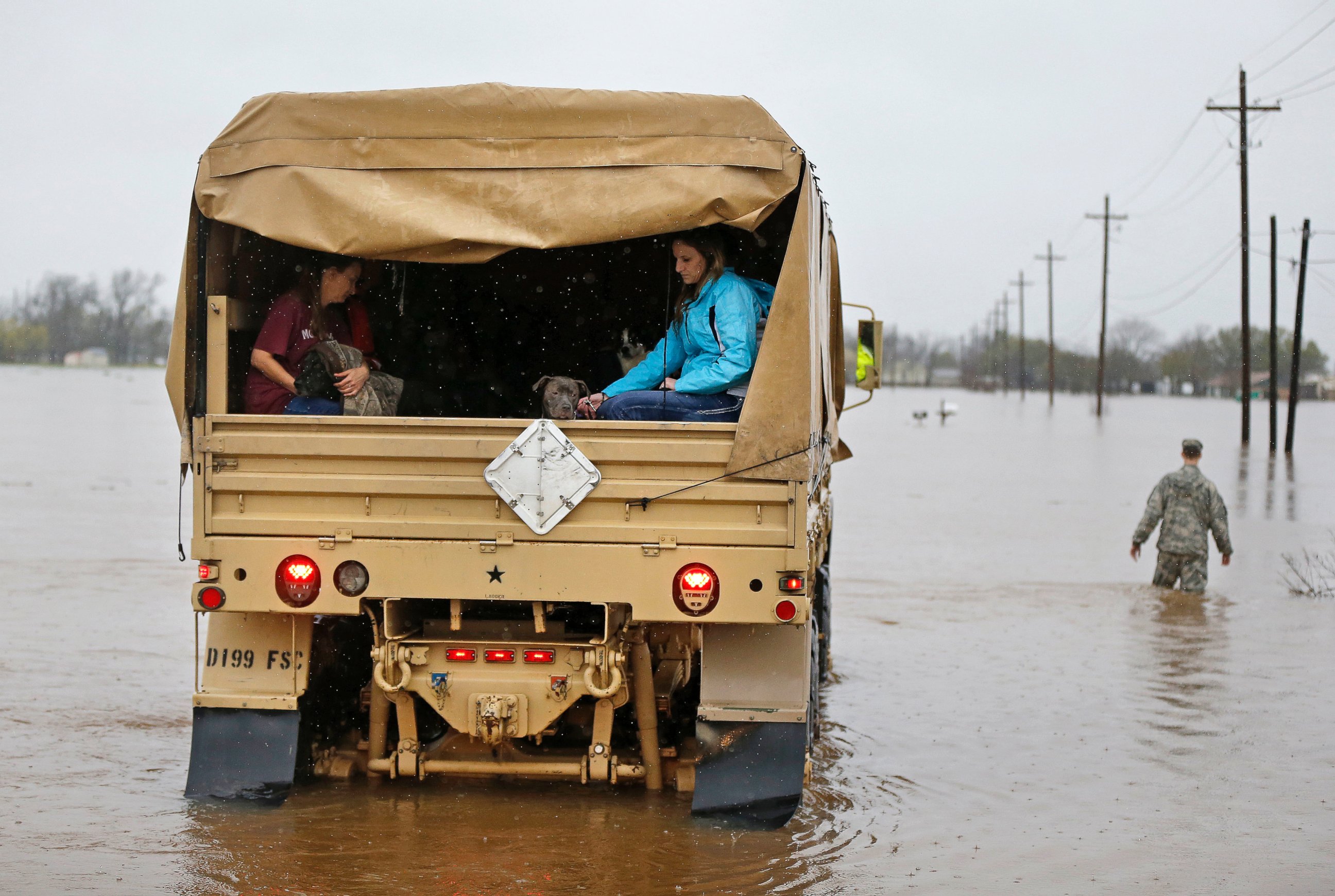 PHOTO: People sit in the back of a Louisiana National Guard truck as they are evacuated from rising floodwaters in Bossier Parish, La., March 10, 2016.
