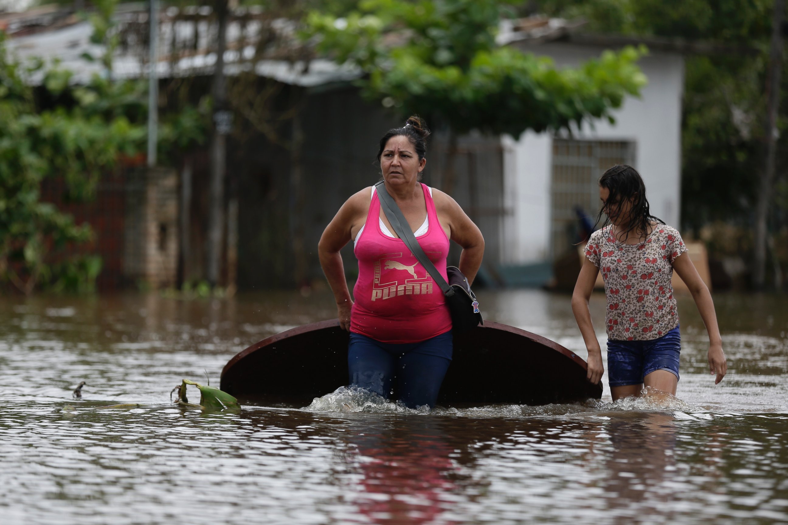 PHOTO:Maria Cristina Olivera and her daughter Catherin carry a table on a flooded street as they leave their home in San Miguel neighborhood in Asuncion, Paraguay, Dec. 27, 2015. 