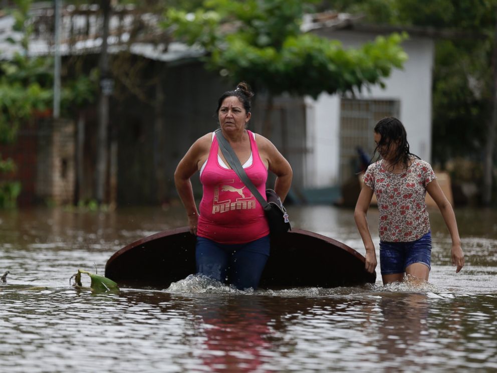 PHOTO:Maria Cristina Olivera and her daughter Catherin carry a table on a flooded street as they leave their home in San Miguel neighborhood in Asuncion, Paraguay, Dec. 27, 2015.