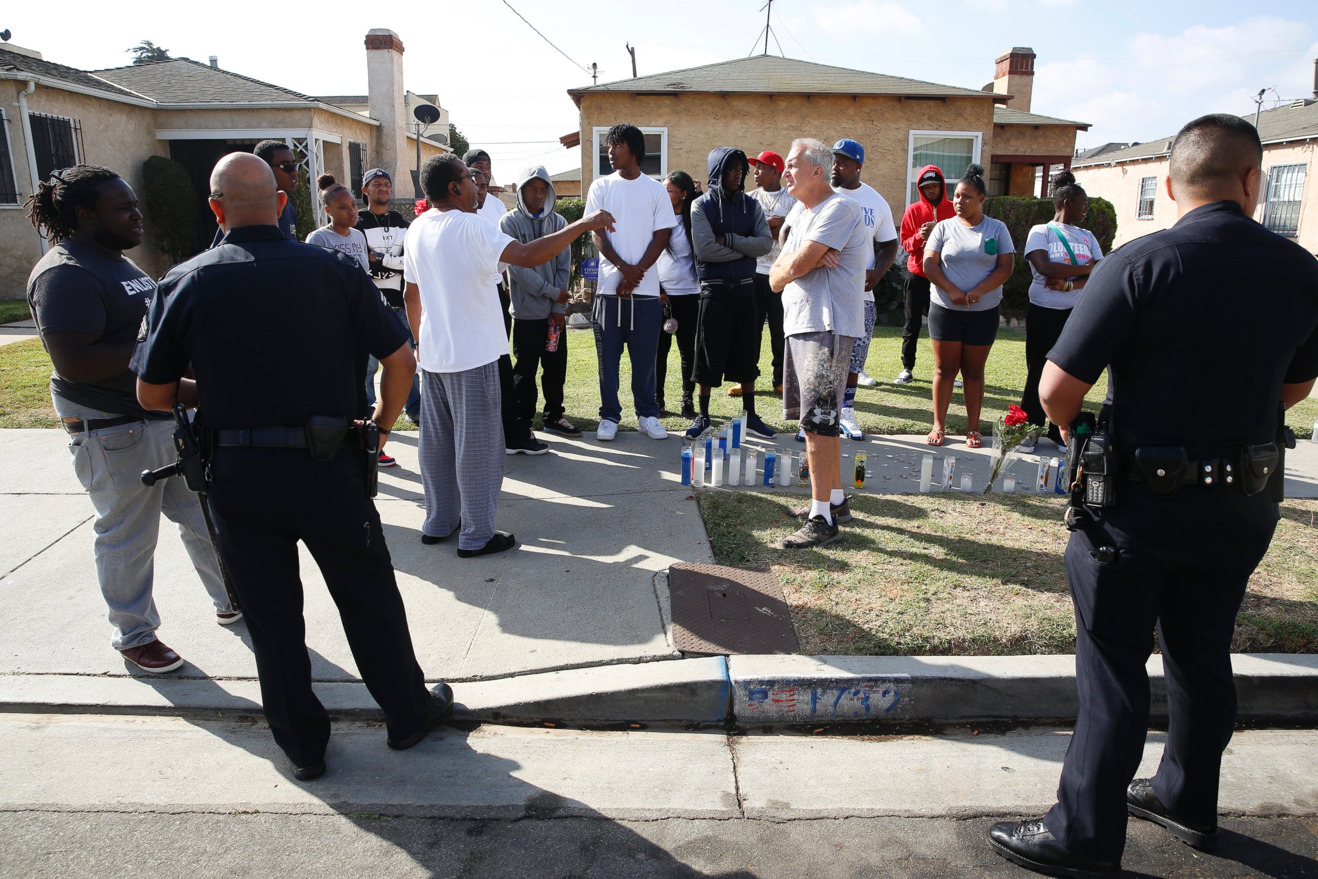 PHOTO: Los Angeles Police officers speak to neighbors and members of the community gathered around a makeshift memorial outside a residence, Oct. 2, 2016.