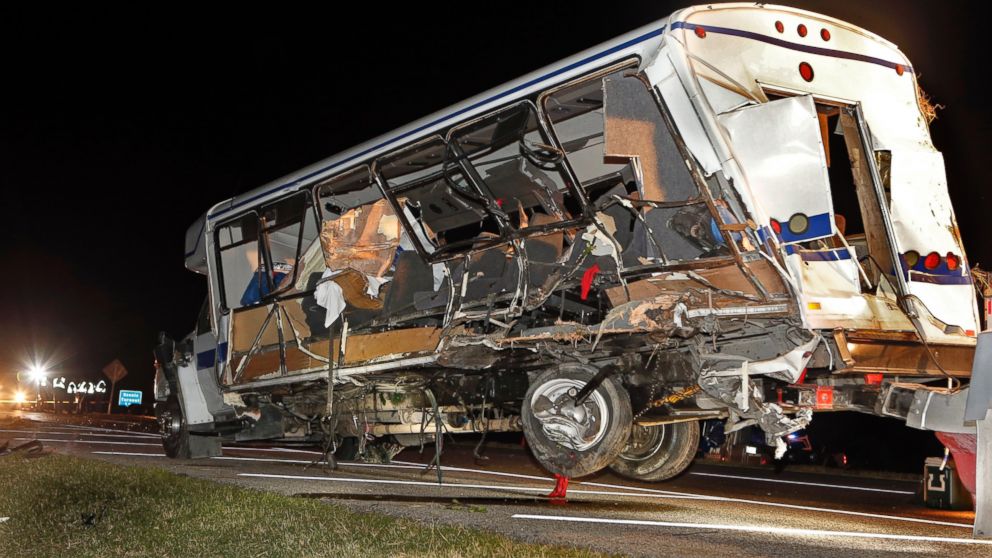 A wrecker removes the team bus as Highway Patrol and emergency personnel work the scene of a fatality accident just south of the Turner Falls area on Saturday, Sept. 27, 2014 in Davis, Okla.  Four members of a Texas college softball team died after a tractor trailer crossed over the center median on Interstate 35 and collided with the team's bus Friday night.