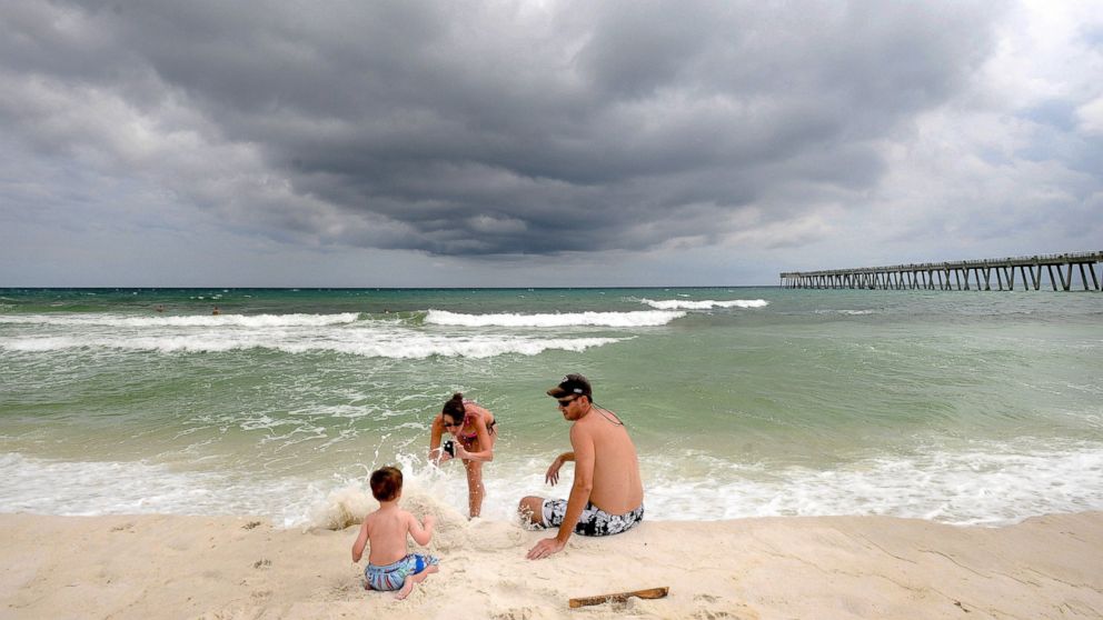 Deanna Smith of Cordele, Ga., takes a photo of her husband, Josh, and their son Noah, 2, on Navarre Beach in Navarre, Fla., as a storm moved into the area, Aug. 29, 2014.