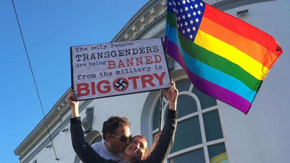 PHOTO: Nick Rondoletto, left, and Doug Thorogood, a couple from San Francisco, wave a rainbow flag and hold a sign against a proposed ban of transgendered people in the military at a protest in the Castro District.