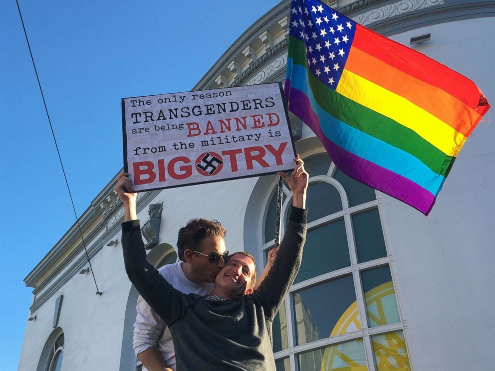 PHOTO: Nick Rondoletto, left, and Doug Thorogood, a couple from San Francisco, wave a rainbow flag and hold a sign against a proposed ban of transgendered people in the military at a protest in the Castro District.