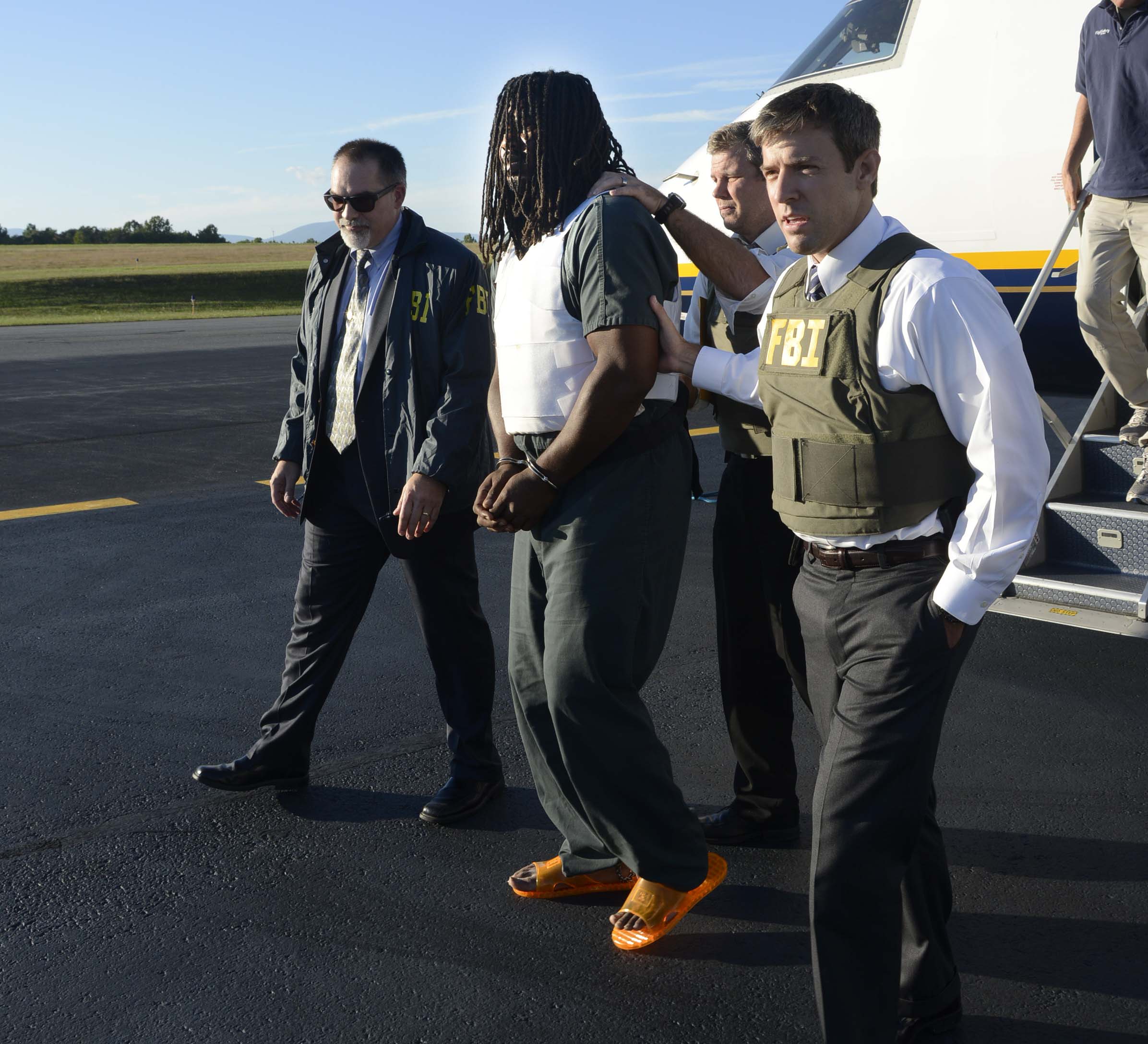 In this Friday, Sept. 26, 2014 photo provided by the FBI, agents escort Jesse Leroy Matthew, Jr., center, from a plane during extradition to Charlottesville, Va.