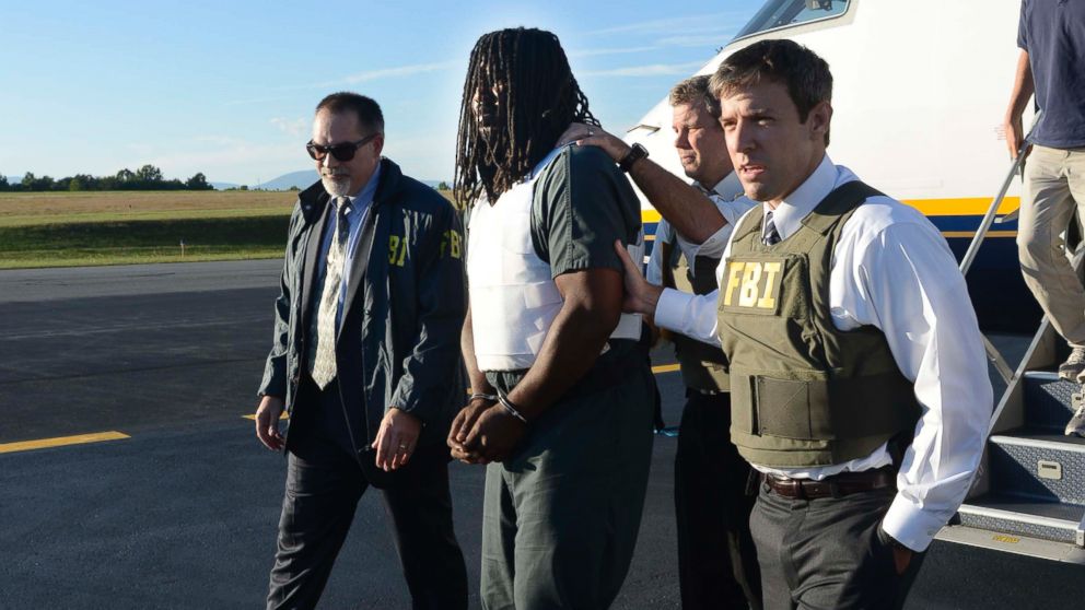 In this Friday, Sept. 26, 2014 photo provided by the FBI, agents escort Jesse Leroy Matthew, Jr., center, from a plane during extradition to Charlottesville, Va.
