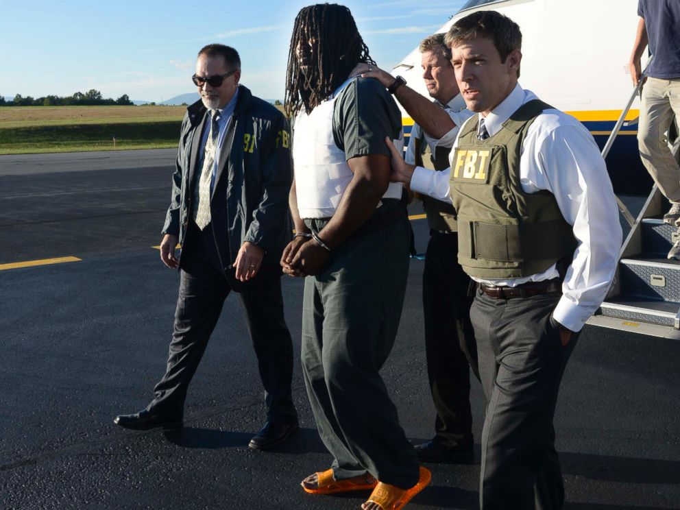 In this Friday, Sept. 26, 2014 photo provided by the FBI, agents escort Jesse Leroy Matthew, Jr., center, from a plane during extradition to Charlottesville, Va.