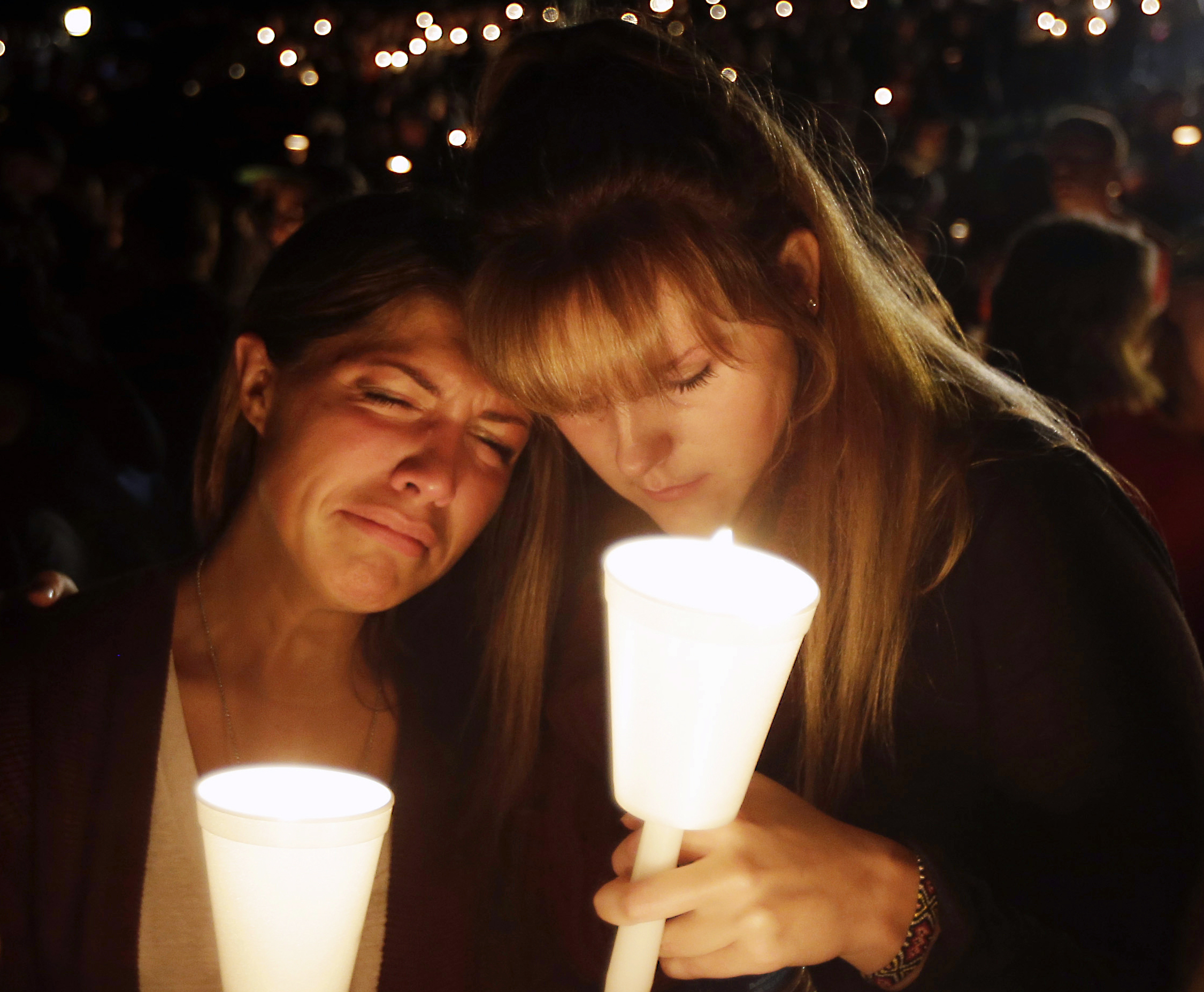 PHOTO: Kristen Sterner, left, and Carrissa Welding, both students at Umpqua Community College, embrace each other during a candlelight vigil for those killed during a shooting at the college, Oct. 1, 2015, in Roseburg, Ore.