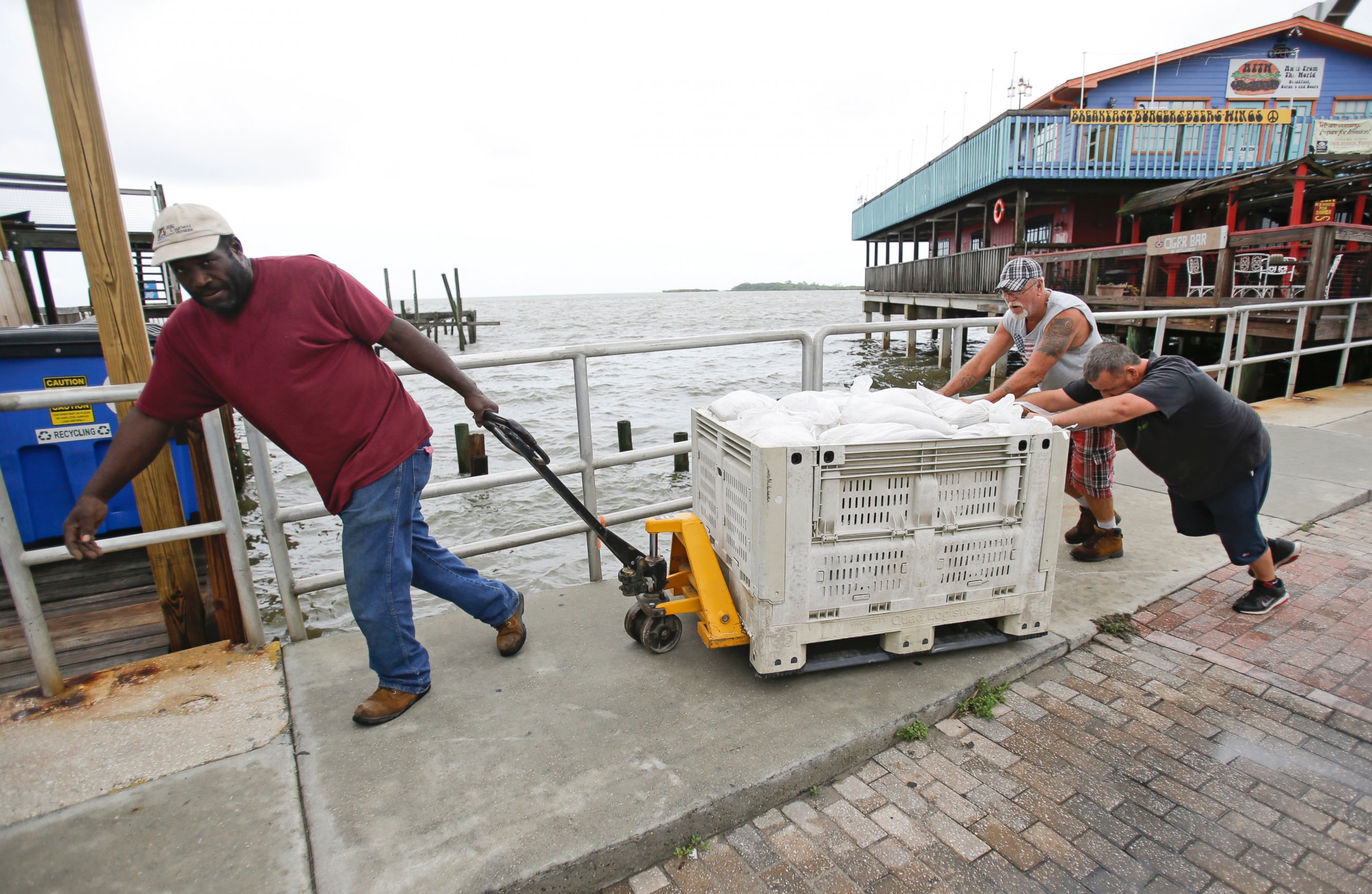PHOTO: Workers move sandbags to protect a restaurant in preperation for Tropical Storm Hermine, Aug. 31, 2016, in Cedar Key, Florida.