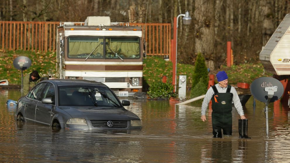 PHOTO:Mike Ewing, co-owner of the Riverview RV Park, wades through floodwaters near a partially submerged car, Dec. 9, 2015, in Puyallup, Wash., after he hooked up a pump to get rid of water that flooded RV's and other vehicles Wednesday morning. 