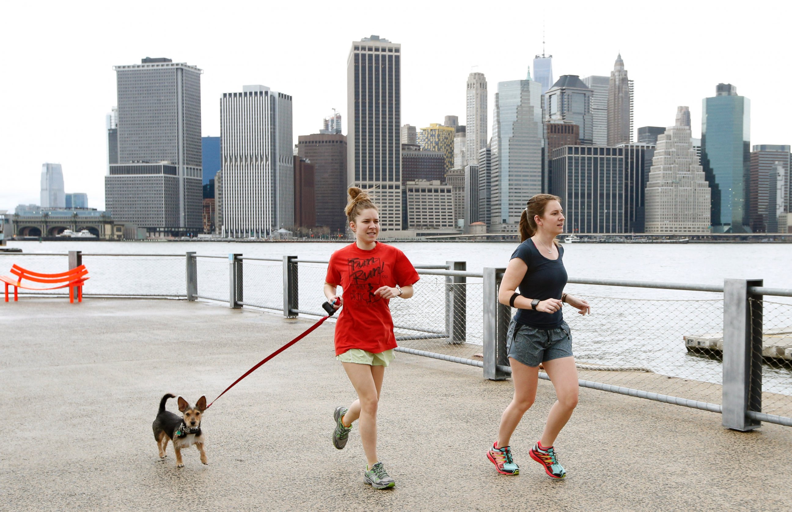 PHOTO: Joggers dressed in shorts and T-shirts run in Brooklyn Bridge Park, in New York, as the Lower Manhattan skyline is seen behind them, Dec. 24, 2015. 
