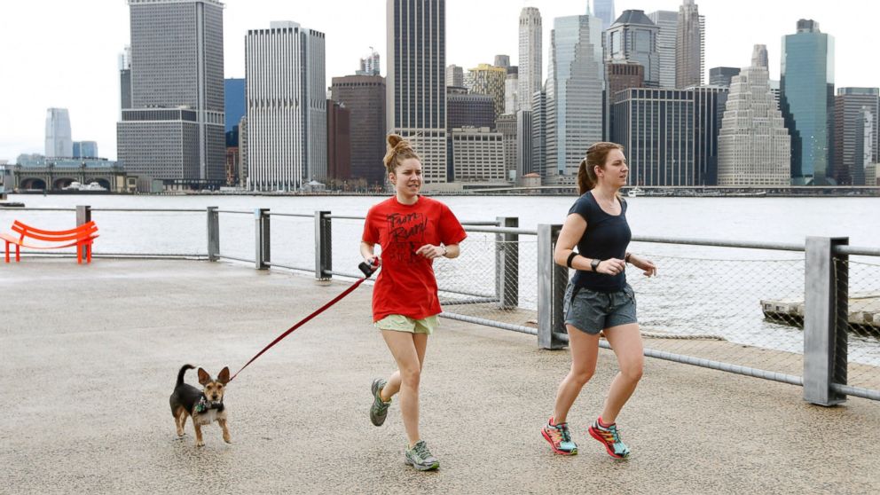 PHOTO: Joggers dressed in shorts and T-shirts run in Brooklyn Bridge Park, in New York, as the Lower Manhattan skyline is seen behind them, Dec. 24, 2015. 