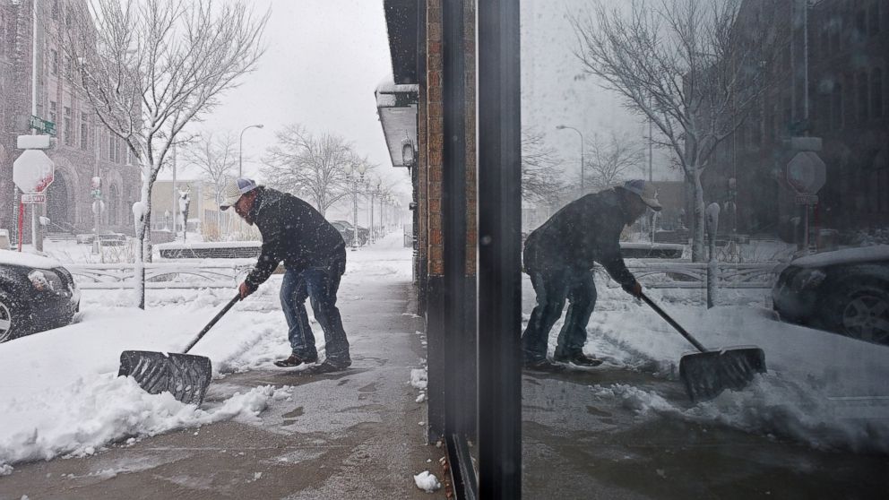 Philip Peter shovels snow in front of the restaurant during a snow storm, Nov. 18, 2016, in Sioux Falls, South Dakota.