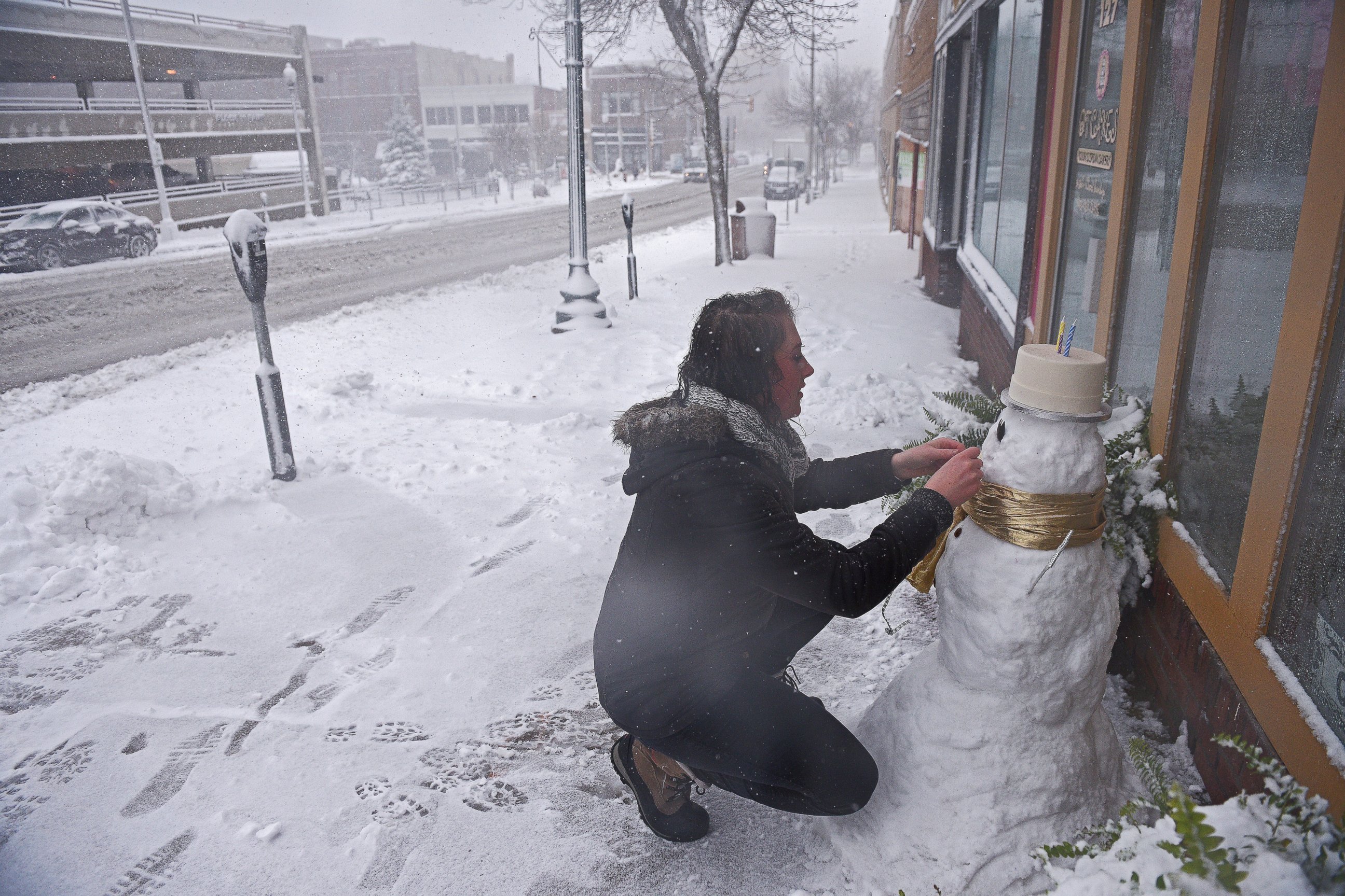 PHOTO: Cassie Maurer, with QT Cakes, puts the finishing touches on a snow man in front of the shop during a snow storm, Nov. 18, 2016, in Sioux Falls, South Dakota. 