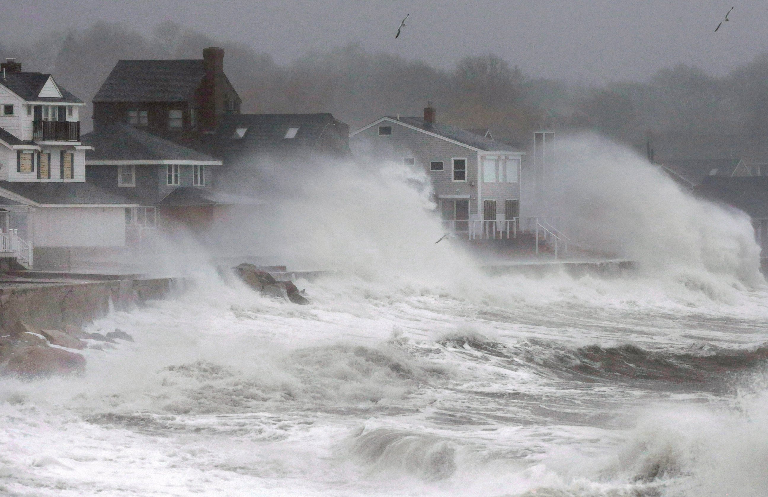 Waves splash against a seawall and onto houses along the Atlantic coast, Tuesday, Dec. 9, 2014, in Scituate, Mass. 