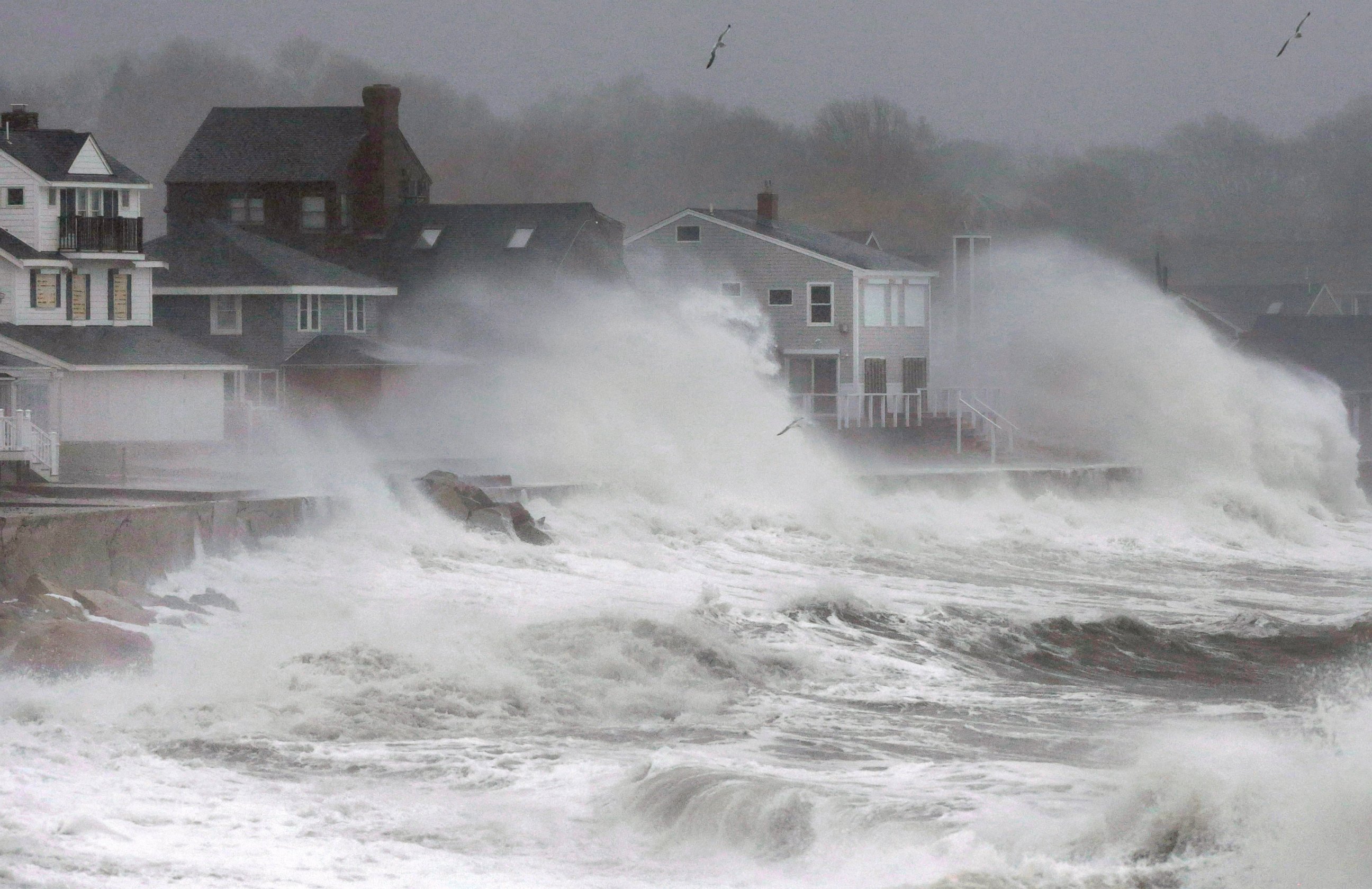 Waves splash against a seawall and onto houses along the Atlantic coast, Tuesday, Dec. 9, 2014, in Scituate, Mass.