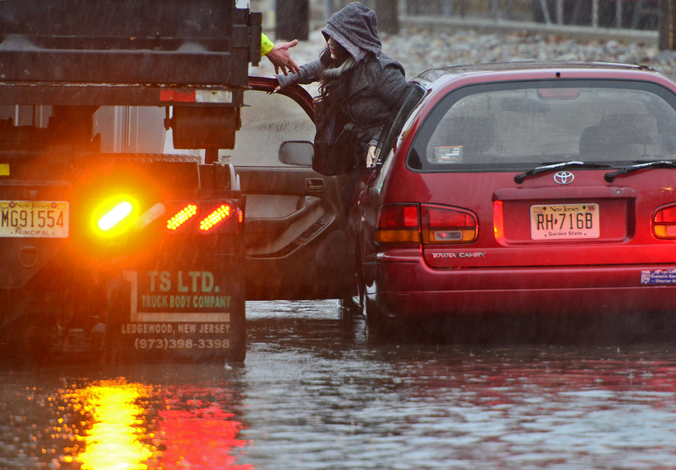 A woman is rescued from rising water after her Toyota Camry station wagon stalled out on West Fort Lee Rd as she approached the Hackensack River Tuesday morning, Dec. 9, 2014, in Bogota, N.J.
