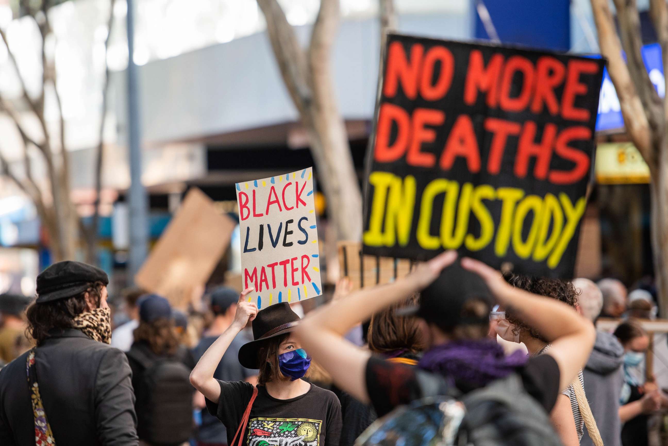 PHOTO: A protester holds a 'Black Lives Matter' and 'No more deaths in custody' placards during a demonstration in Brisbane, Australia, June 6, 2020.
