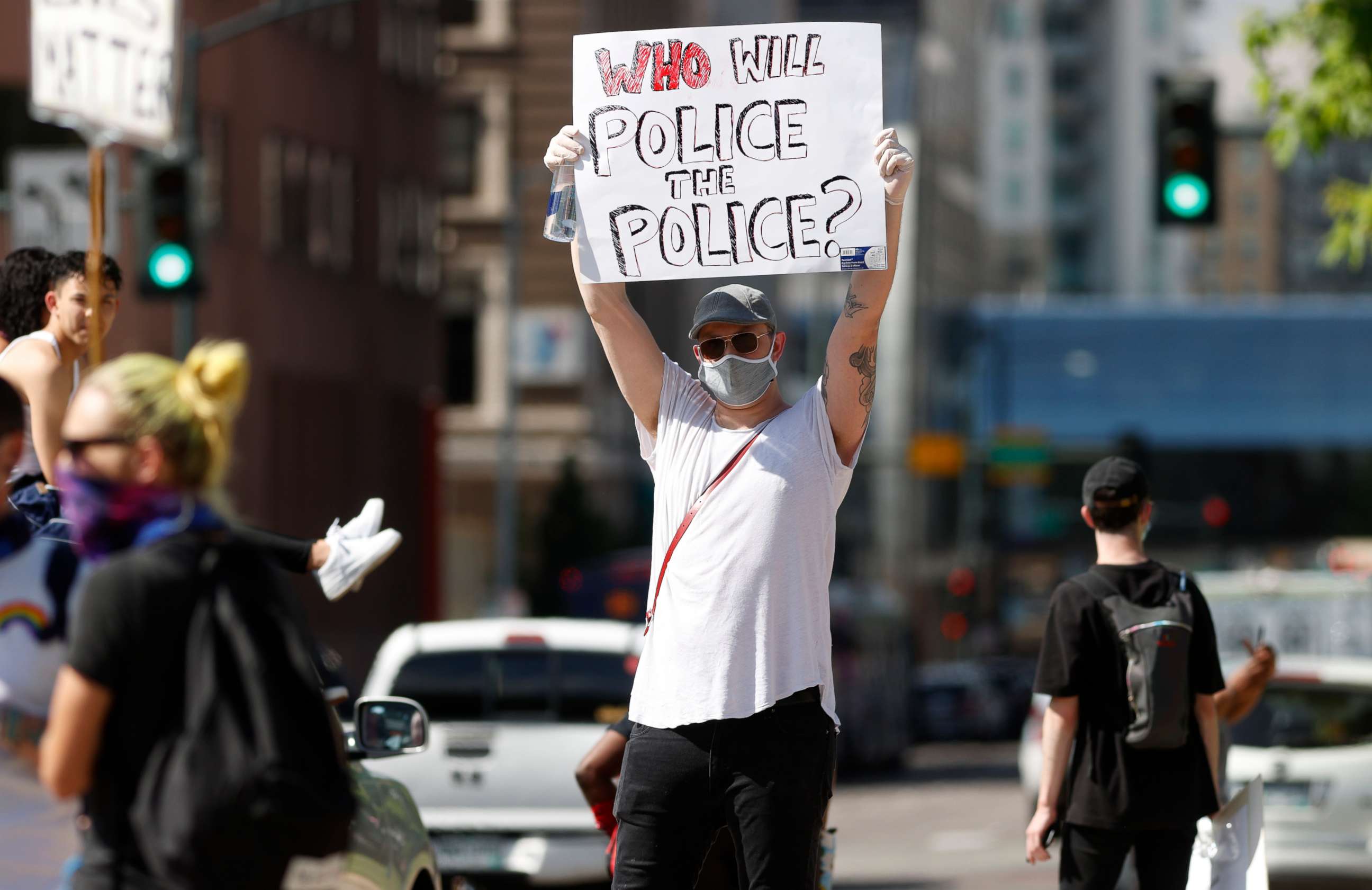 PHOTO: A demonstrator wears a face mask and latex gloves while waving a placard along Lincoln Avenue during a protest Tuesday, June 2, 2020, in Denver over the death of George Floyd, a handcuffed black man in police custody in Minneapolis. 