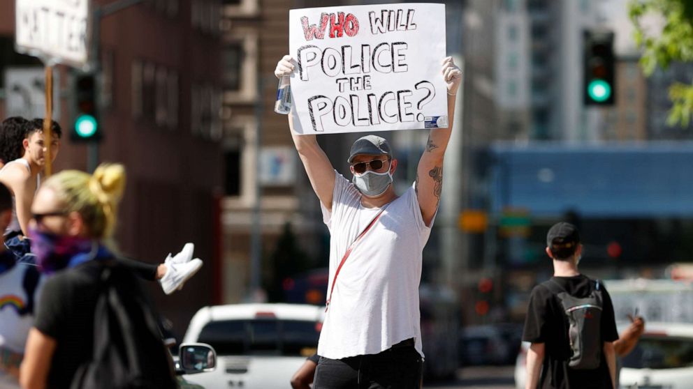 PHOTO: A demonstrator wears a face mask and latex gloves while waving a placard along Lincoln Avenue during a protest Tuesday, June 2, 2020, in Denver over the death of George Floyd, a handcuffed black man in police custody in Minneapolis. 