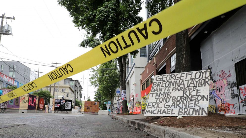 PHOTO: Caution tape is shown near a sign with the names of victims of police violence, Saturday, June 20, 2020, at the Capitol Hill Occupied Protest zone in Seattle. It is unknown who put the tape in place. 