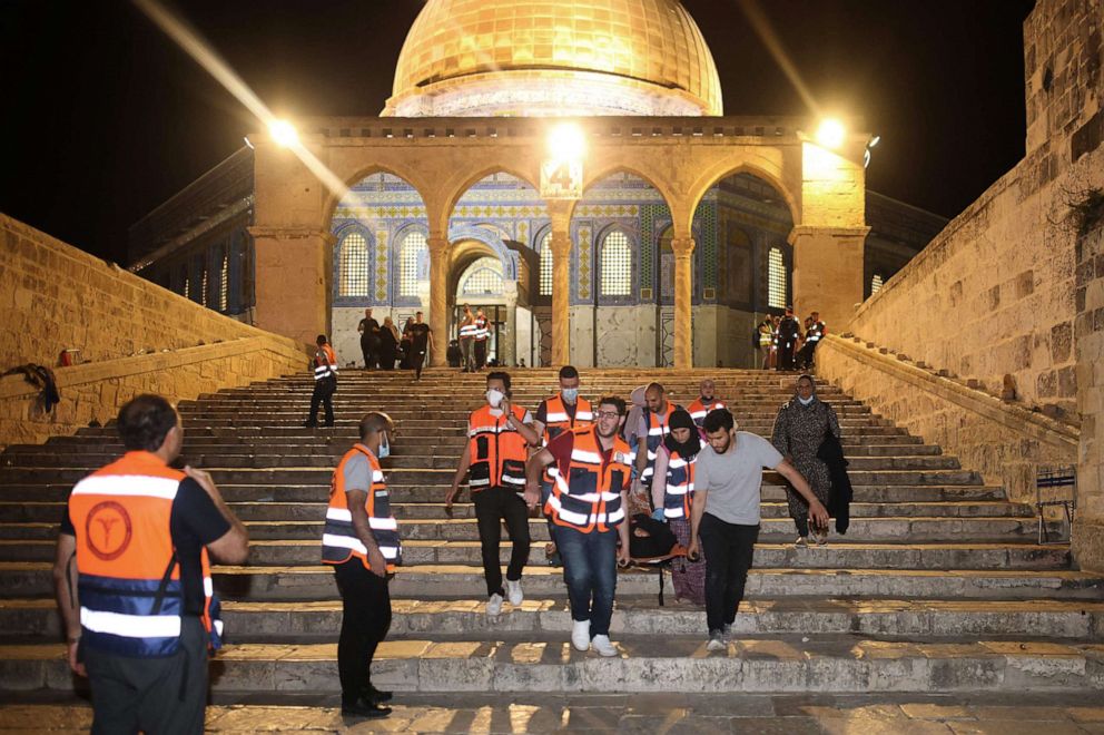 PHOTO: Palestinian medics evacuate a wounded person during clashes between Israeli security forces and Palestinian protestors in Jerusalem's al-Aqsa mosque compound, May 10, 2021. 