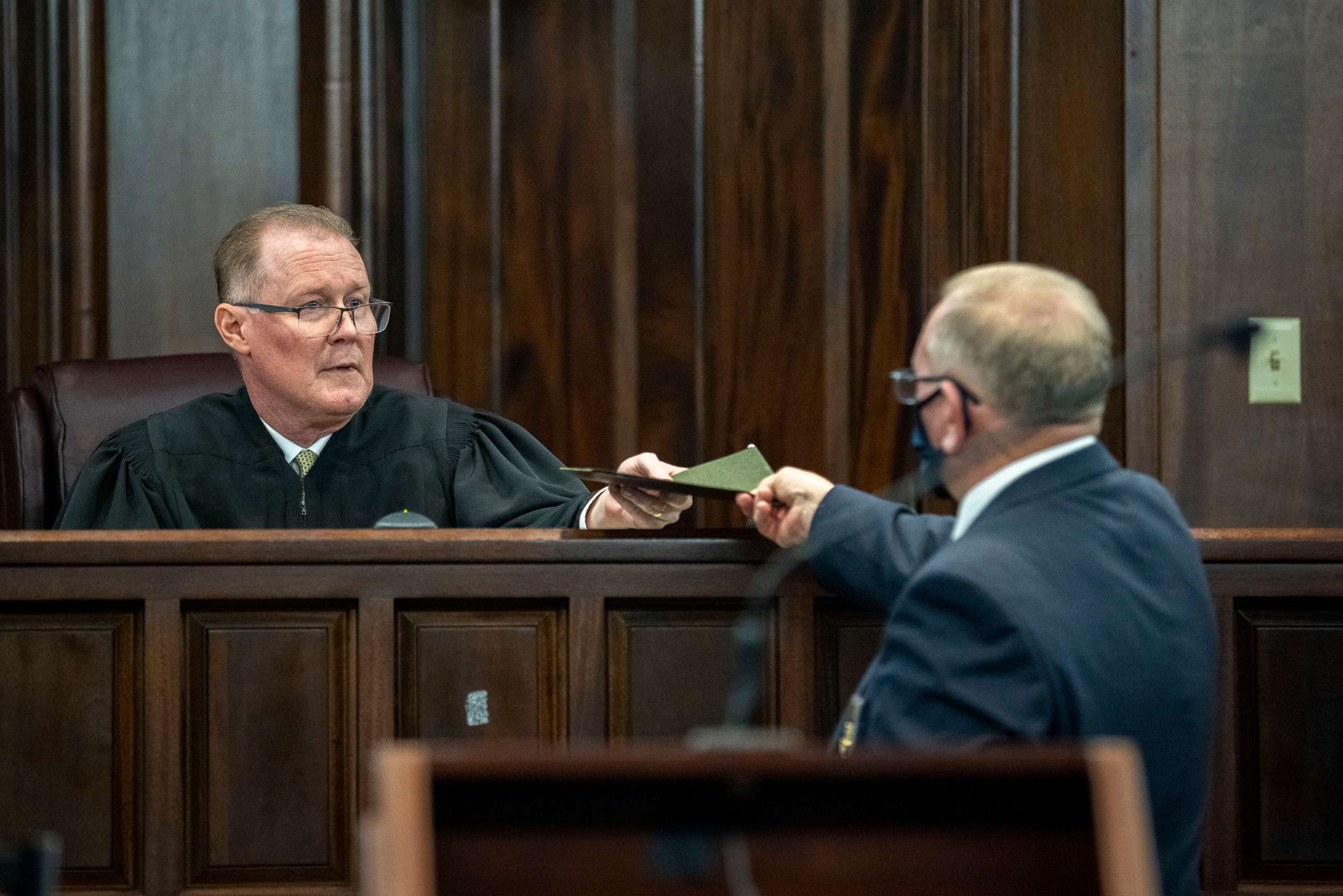 PHOTO: Superior Court Judge Timothy Walmsley is handed the jury's verdict from a bailiff during the trial of Greg McMichael and his son, Travis McMichael, and a neighbor, William "Roddie" Bryan, Nov. 24, 2021, in Brunswick, Ga.